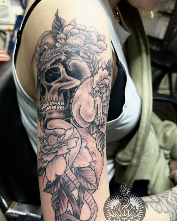 Black and grey skull with peonies on an upper arm