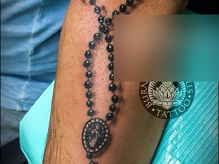 Black and grey rosary on a forearm