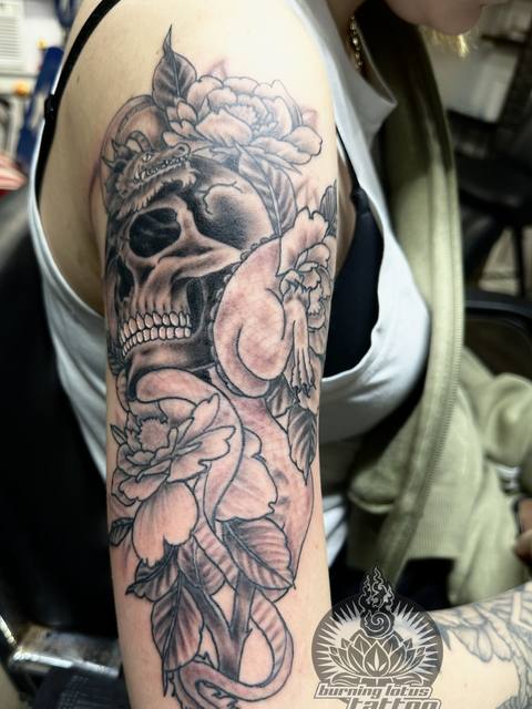 Black and grey skull with peonies on an upper arm