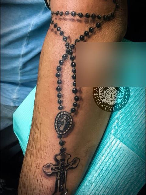 Black and grey rosary on a forearm