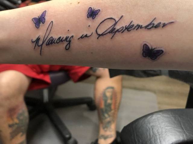 Script lettering with small butterflies on a forearm